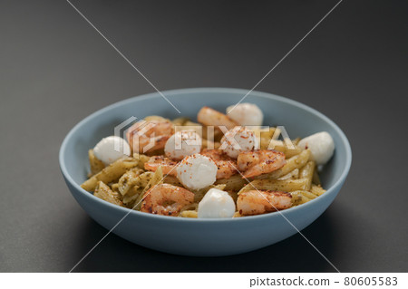 Penne pasta with shrimps and mozzarella and pesto in blue bowl Penne pasta with shrimps and mozzarella and pesto in blue bowl 80605583