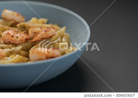 Penne pasta with shrimps and pesto in blue bowl with copy space 80605607