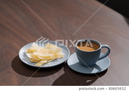 Fresh espresso in blue cup with cheese flakes on walnut table Fresh espresso in blue cup with cheese flakes on walnut table 80605632