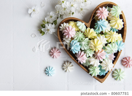 Small colorful meringues in the  wooden heartshaped bowl 80607781