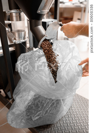 Young specialist worker is roasting coffee in hangar 80608386