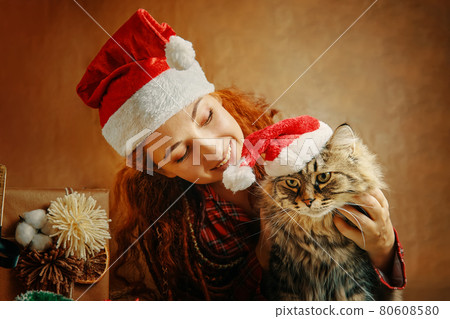 Woman in Santa Claus hat with cat in Christmas hat. Woman in Santa Claus hat with cat in Christmas hat. 80608580