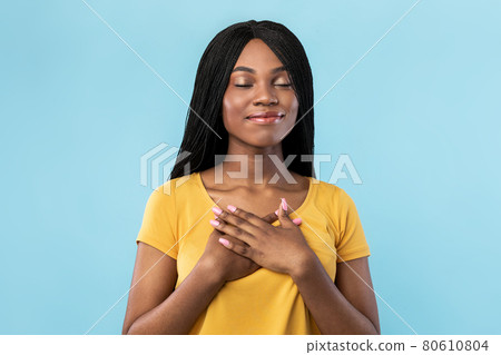 Grateful African American Woman Pressing Hands To Chest, Blue Background Grateful African American Woman Pressing Hands To Chest, Blue Background 80610804