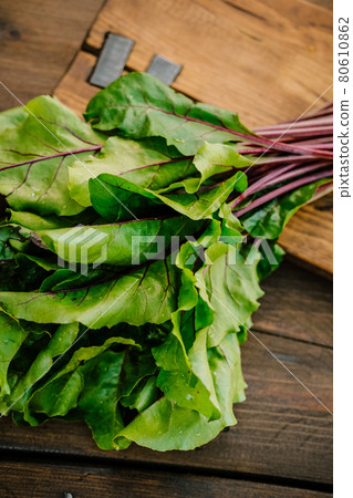 beet leaves on wooden background. beet tops lies on a cutting board beet leaves on wooden background. beet tops lies on a cutting board 80610862