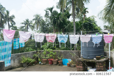 Baby clothes on the roof hang up in Sunlight. Clothes hung on clothesline for drying on terrace of residential house. Kolkata India July 21, 2021 Baby clothes on the roof hang up in Sunlight. Clothes hung on clothesline for drying on terrace of residential house. Kolkata India July 21, 2021 80611567