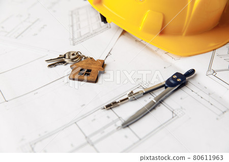 Construction plans with yellow helmet, house keys and drawing tools on a table Construction plans with yellow helmet, house keys and drawing tools on a table 80611963