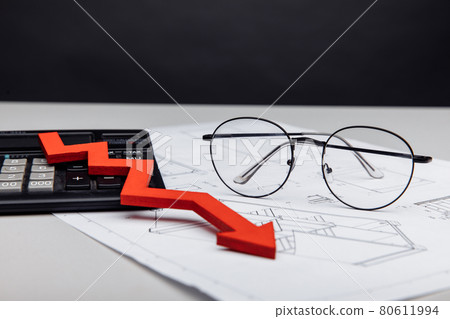 Financial and investment concept. Glasses, calc and arrow down on architectural project close-up Financial and investment concept. Glasses, calc and arrow down on architectural project close-up 80611994