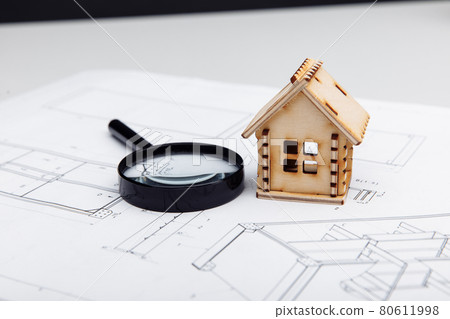Mini model of house and a magnifying glass on a drawing. Real estate building concept Mini model of house and a magnifying glass on a drawing. Real estate building concept 80611998