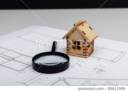Miniature house and a magnifying glass on a drawing. Real estate building concept 80611999