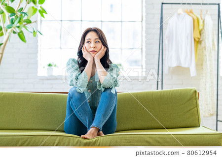 Young woman sitting on the couch in the living room 80612954