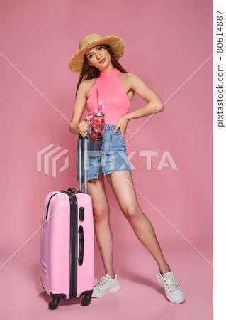 Tourist woman in summer casual clothes holding fresh beverage and suitcase on pink background 80614887