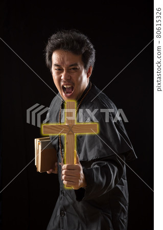 Young Asian Priest show lighting crucifix while holding bible to exorcise ghost Young Asian Priest show lighting crucifix while holding bible to exorcise ghost 80615326