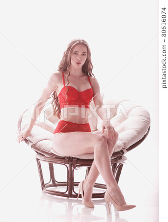 beautiful woman in red underwear sitting in a chic armchair 80616074