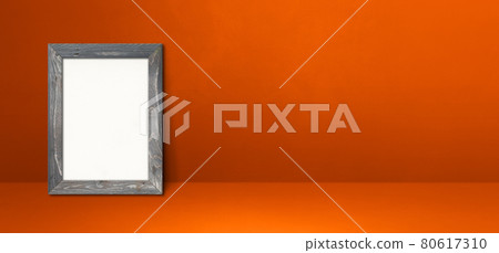 Wooden picture frame leaning on an orange wall. Horizontal banner 80617310