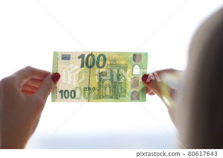 Woman checks authenticity of hundred euro bill Woman checks authenticity of hundred euro bill 80617643