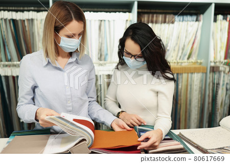 Seller with buyer in medical protective masks communicate in fabric store Seller with buyer in medical protective masks communicate in fabric store 80617669