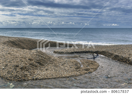 Fresh water stream going into the sea with visible sun rays - Cornwall, United Kingdom 80617837