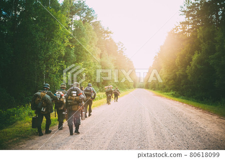 Unidentified re-enactors dressed as German soldiers during march through forest Unidentified re-enactors dressed as German soldiers during march through forest 80618099