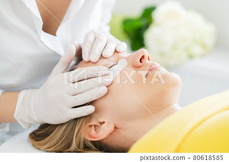 Woman receiving eyelash extension in salon 80618585