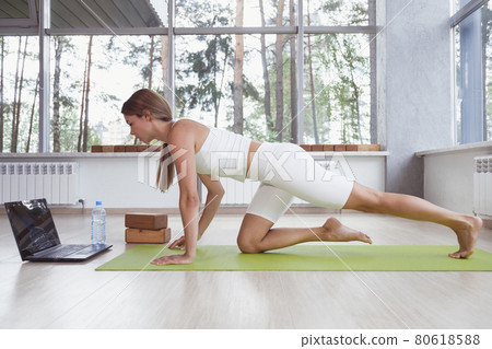 Young fit woman in sportswear doing sport or yoga online with laptop. Remote workouts, online trainer. 80618588