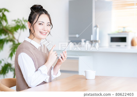一個年輕的女人,在客廳裡操作智能手機 一個年輕的女人,在客廳裡操作智能手機 80622403