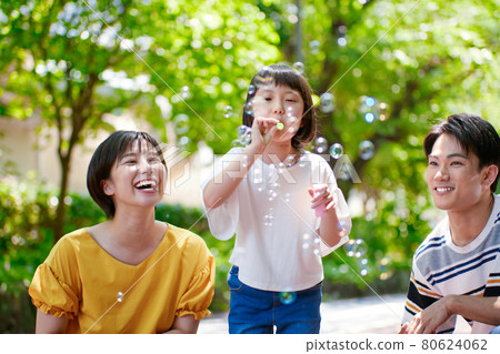 Young family playing with soap bubbles Young family playing with soap bubbles 80624062