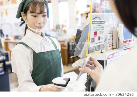 Non-contact image of a female employee scanning a smartphone at a supermarket cashier with infection control 80624286