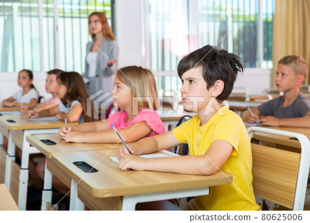 Schoolkids sitting at desks 80625006