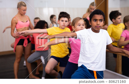 Boys and girls training along ballet bar 80625160