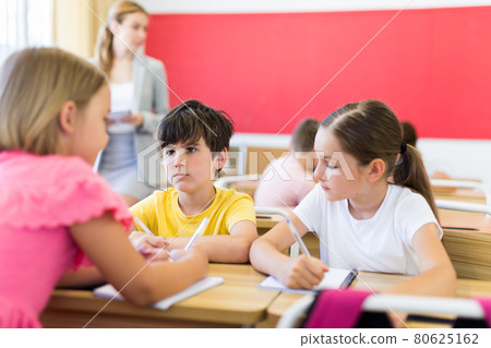Interested preteen pupils discussing learning material in groups Interested preteen pupils discussing learning material in groups 80625162