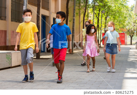 School children in protective medical masks walk along the street of a city School children in protective medical masks walk along the street of a city 80625275