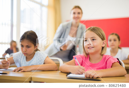 Two positive small school girls sitting together in classroom Two positive small school girls sitting together in classroom 80625480