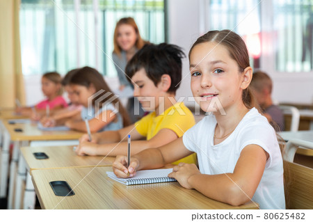 Schoolgirl sitting in classroom during lesson in elementary school Schoolgirl sitting in classroom during lesson in elementary school 80625482