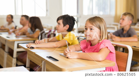 Schoolgirl sitting in classroom during lesson in elementary school 80625505