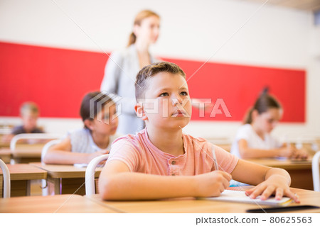 Boy and classmates sitting in classroom 80625563