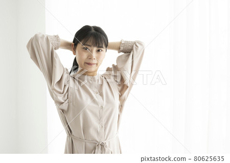 一個年輕女子在窗邊綁頭髮 一個年輕女子在窗邊綁頭髮 80625635