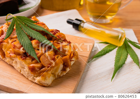 Homemade pizza with marijuana or cannabis leaf on wooden tray. 80626453