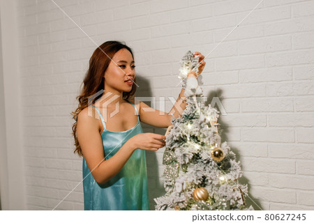 Pensive young pretty asian woman with burning candles on Christmas eve making wish 80627245