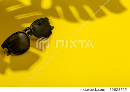 Summer and vacation concept. Sunglasses in the shadow of tropical truths and plants on a bright clean summer background 80628735