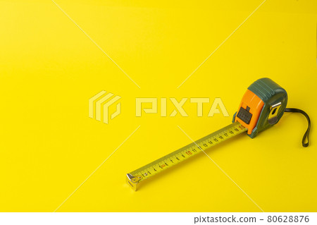 Repair, construction and tools background. Measuring tape on a yellow background. Copy space 80628876