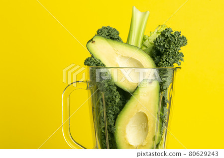 Smoothie recipe. Green smoothie of vegetables avocado, celery, cale salad, spinach in a blender on a yellow background. Vegan and healthy food detox concept 80629243