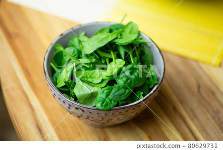 Fresh spinach leaves in a bowl on a wooden table. Eco vegan spinach salad 80629731