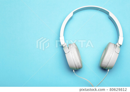 Musical headphones on a colored blue background. Aesthetics retro 80s and minimal concept Musical headphones on a colored blue background. Aesthetics retro 80s and minimal concept 80629812