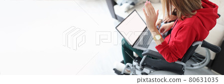 Disabled woman in wheelchair waving hand at laptop screen 80631035