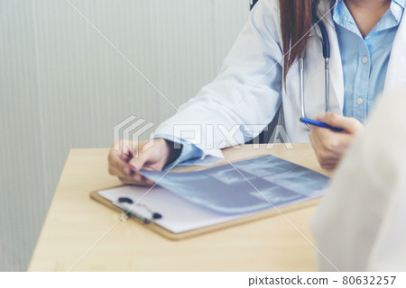 Two asian women doctors discuss meeting doctor's office medical clinic looking x-ray film consulting patient disease. Asian medical lab young women talking together discussing healthcare teamwork Two asian women doctors discuss meeting doctor's office medical clinic looking x-ray film consulting patient disease. Asian medical lab young women talking together discussing healthcare teamwork 80632257