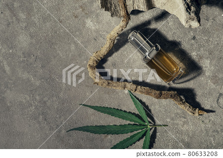 Glass bottle with CBD oil, THC tincture and hemp leaf on gray marble background. naturalness. CBD oil cosmetics. 80633208