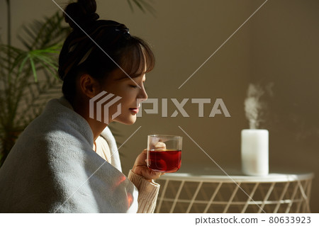 Young woman relaxing at home with a cup of fruit tea 80633923