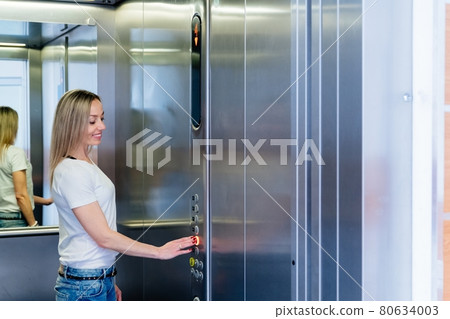 Happy blonde woman pushing elevator button. Happy blonde woman pushing elevator button. 80634003
