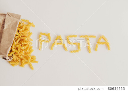 Spiral pasta in a paper bag on a white background with the inscription pasta. Top view. Copy, empty space for text 80634333