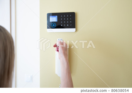 Woman hand using remote to operate entrance security system. Woman hand using remote to operate entrance security system. 80638054